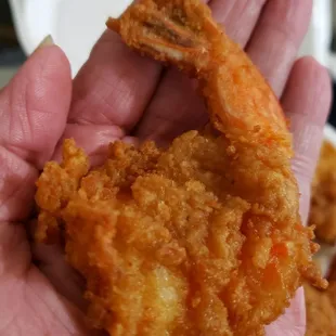 a hand holding a fried shrimp