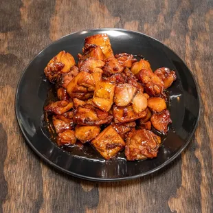 a black plate of food on a wooden table