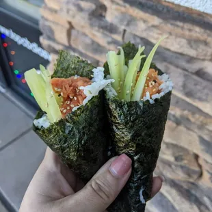  a hand holding two pieces of sushi