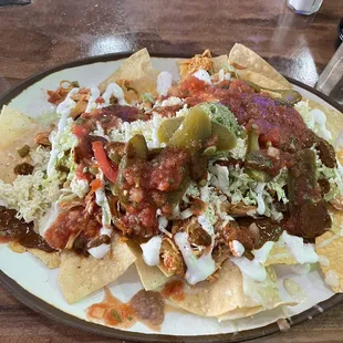 NACHOS SUPREME has chicken, guacamole, queso, salsa, jalapeños, sour cream.