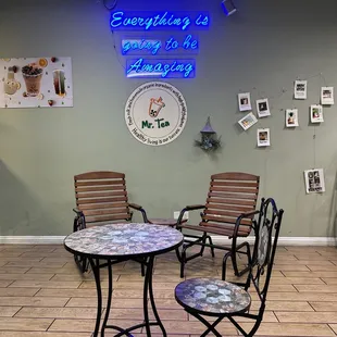 two chairs and a table with a neon sign on the wall