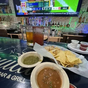 two bowls of soup and tortillas on a bar