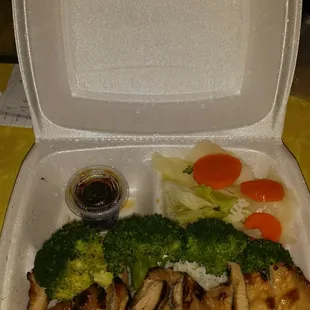 a take out container with broccoli, mushrooms, and carrots