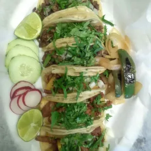 a plate of tacos with pickles and cucumbers