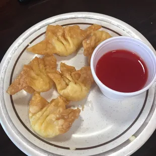 a plate of dumplings and a cup of sauce