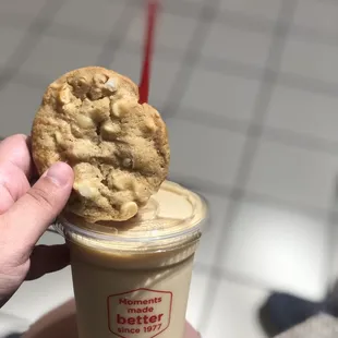 a hand holding a cookie and milk shake