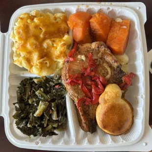 Smothered pork chop with mac and cheese, greens, sweet potatoes, mash potatoes and biscuit.