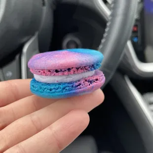 a hand holding a colorful macaron