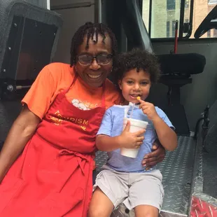 a woman and child sitting on the back of a truck
