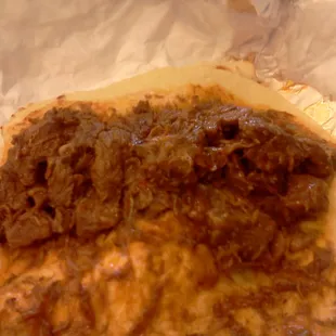 This is a taco of carne guisada in a flour tortilla. The taco tastes very good.
