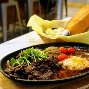 CS1. Cast Iron Skillet - Vietnamese Bo Ne: marinated rib eye steaks, fried egg, homemade pate, onion, tomatoes ($22).