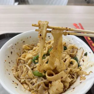 a bowl of noodles with chopsticks