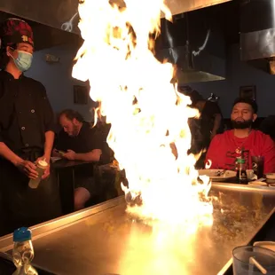 a man in a face mask standing in front of a fire