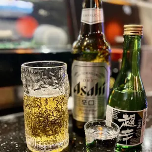 a glass of beer and a bottle of sake