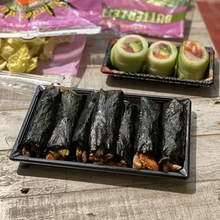 a tray of sushi rolls and a bag of chips