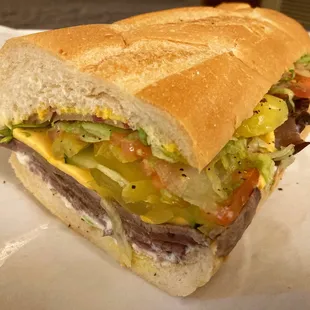 a sub sandwich with meat, lettuce, tomato, and cheese