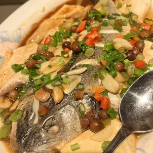 a plate of fish with vegetables and a spoon