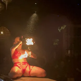 a woman sitting on a bar with fire