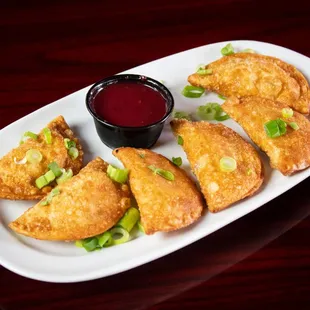 a plate of fried dumplings with dipping sauce