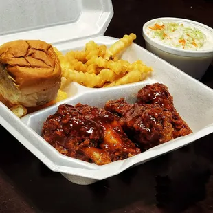 a tray of chicken wings, french fries and coleslaw