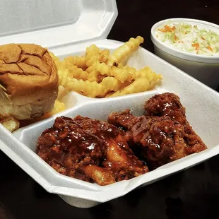 a tray of food including a sandwich, fries, and coleslaw