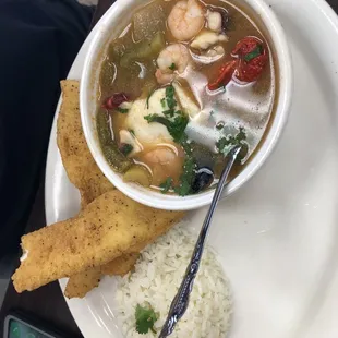 a bowl of soup with a spoon and a piece of bread on a plate