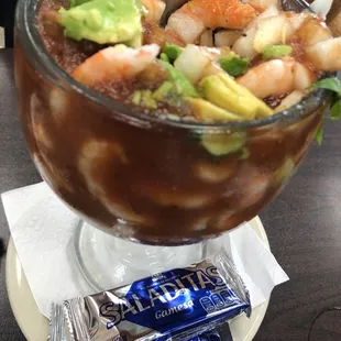 a glass bowl of soup with shrimp, avocado, and guacamole
