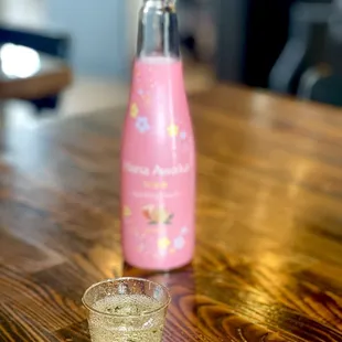 a pink bottle and a glass on a wooden table