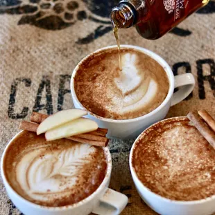 two mugs of coffee with apple slices and cinnamon