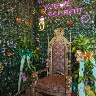 a chair in front of a wall of plants