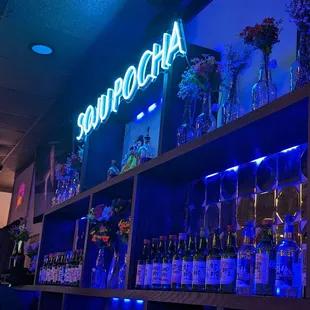 a shelf of liquor bottles and a neon sign