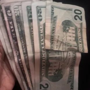 a hand holding a stack of twenty dollar bills