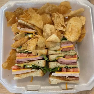 a sandwich and chips in a styrofoam container