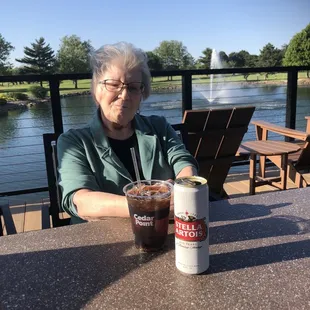a woman sitting at a table with a drink