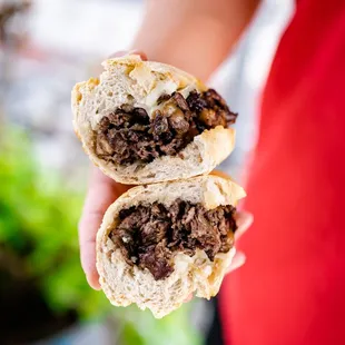 a person holding a sandwich with meat