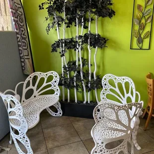 two white chairs in front of a green wall