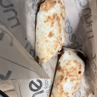 two burritos wrapped in paper