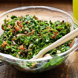 a salad in a bowl with a wooden spoon