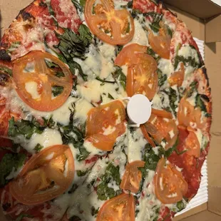 Thin crust pizza with vegan cheese, spinach, basil and tomatoes.