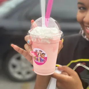 a woman holding a pink drink