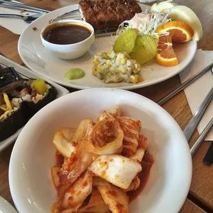 Kimchi and fried pork with sides and sauce.