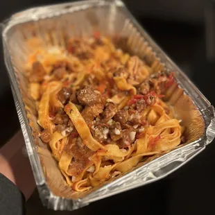 a hand holding a pan of pasta