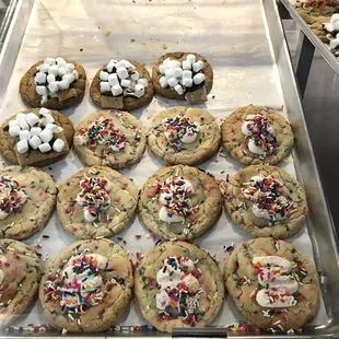 a tray of cookies with marshmallows and sprinkles