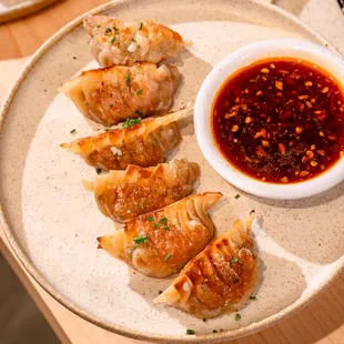 a plate of dumplings and a bowl of sauce