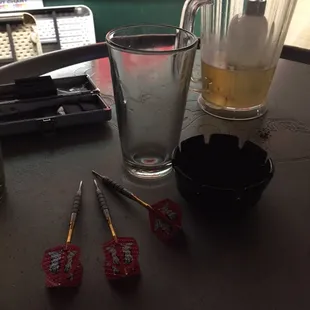a glass of beer, darts, and darts