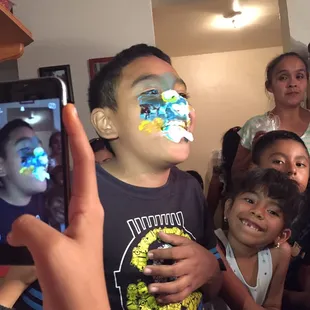 a young boy taking a selfie with his face painted