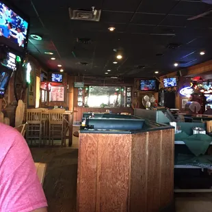 a man in a pink shirt sitting at a bar