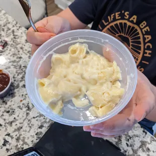 a person holding a bowl of macaroni and cheese