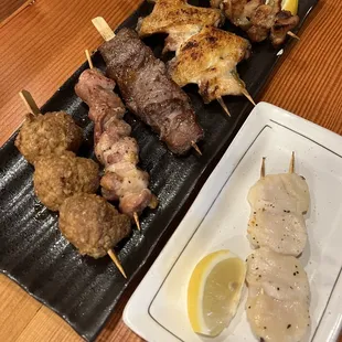 a plate of meat skewers and a plate of lemon wedges