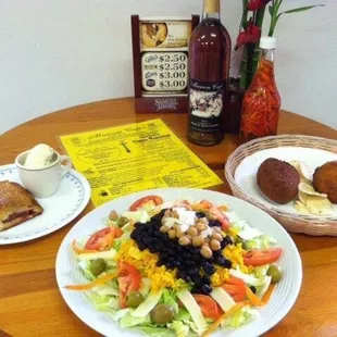 a plate of salad, bread, and a bottle of wine